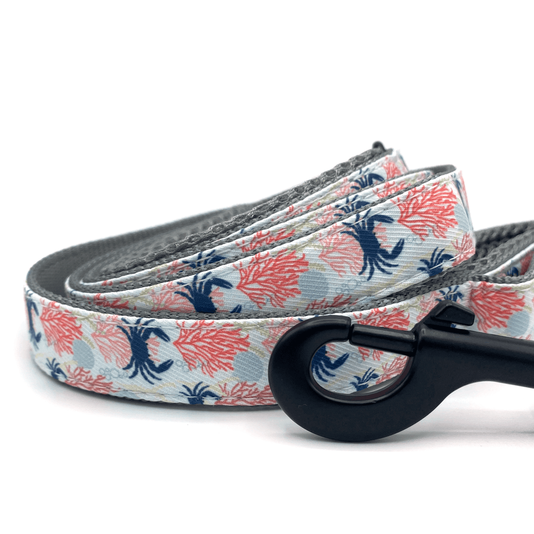 a dog leash with blue crabs, seashells, and pink corals with black hardware and light grey padded handles